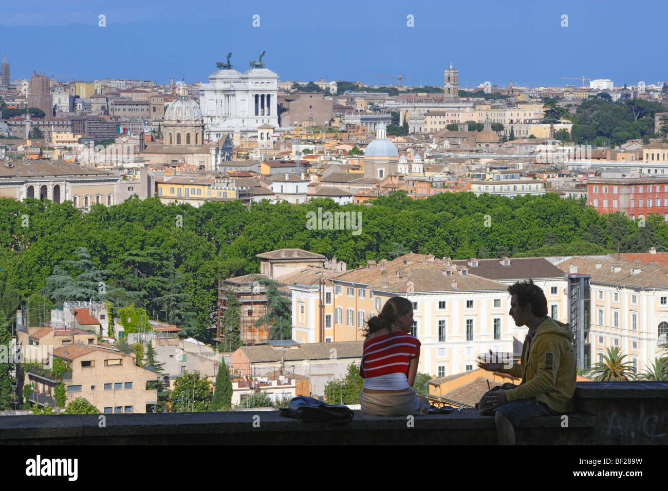 Two people sitting on a wall, view over the town of Rome, Italy, Europe Stock Photo
