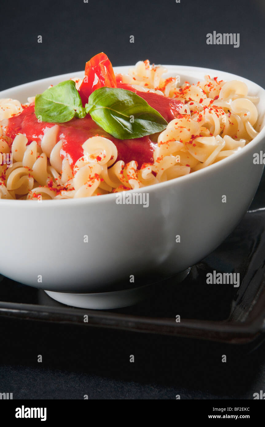 Closeup of rotini pasta topped with tomato sauce and basil Stock Photo