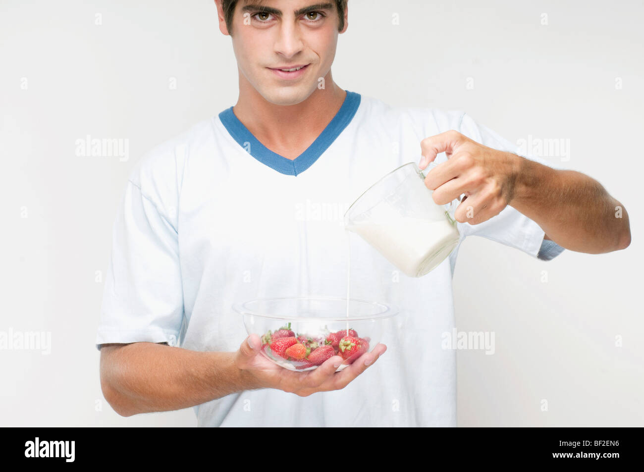 Portrait of a man pouring milk on strawberries Stock Photo
