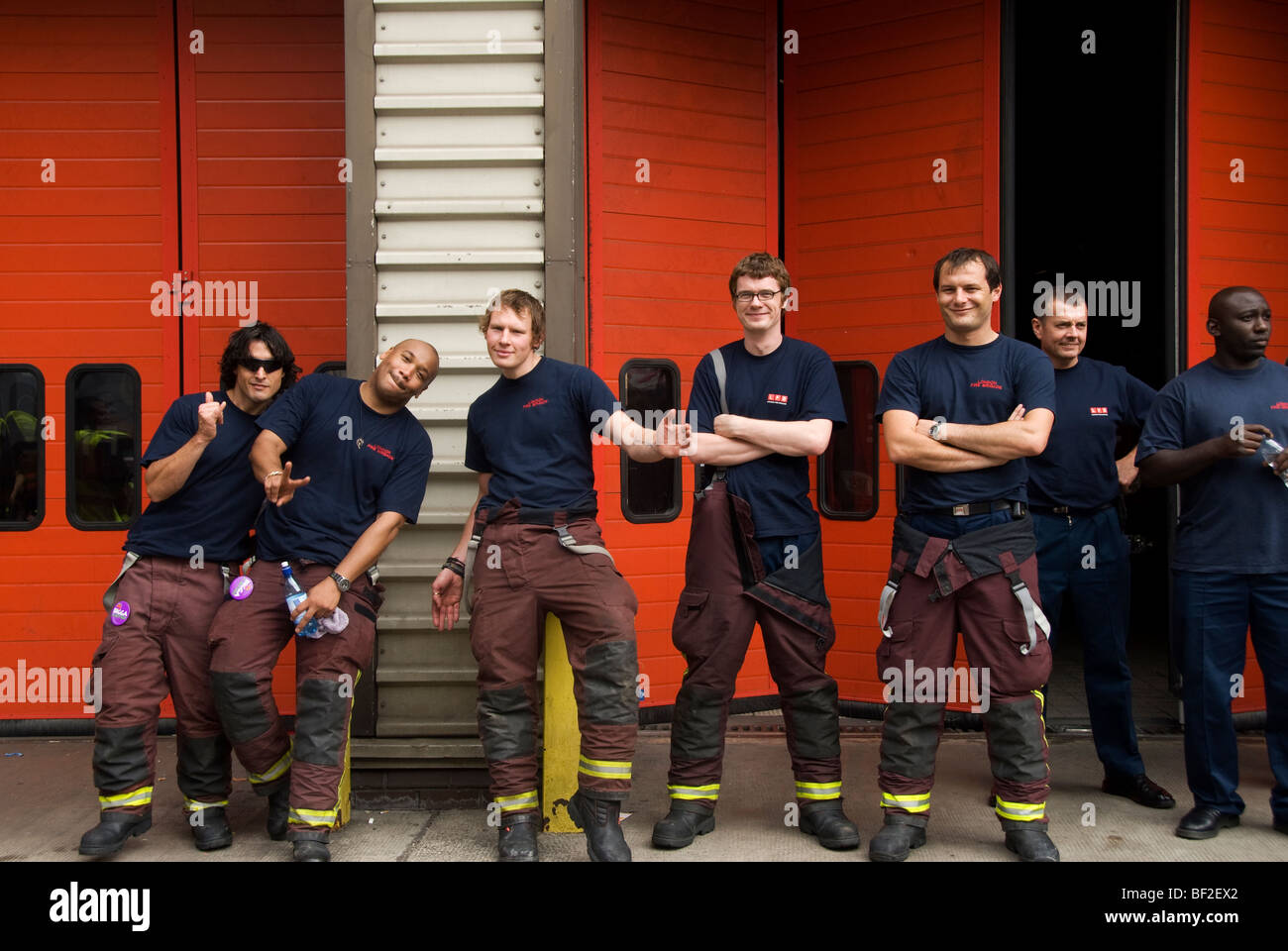 Group of firemen fooling around in front of fire station West London Stock Photo