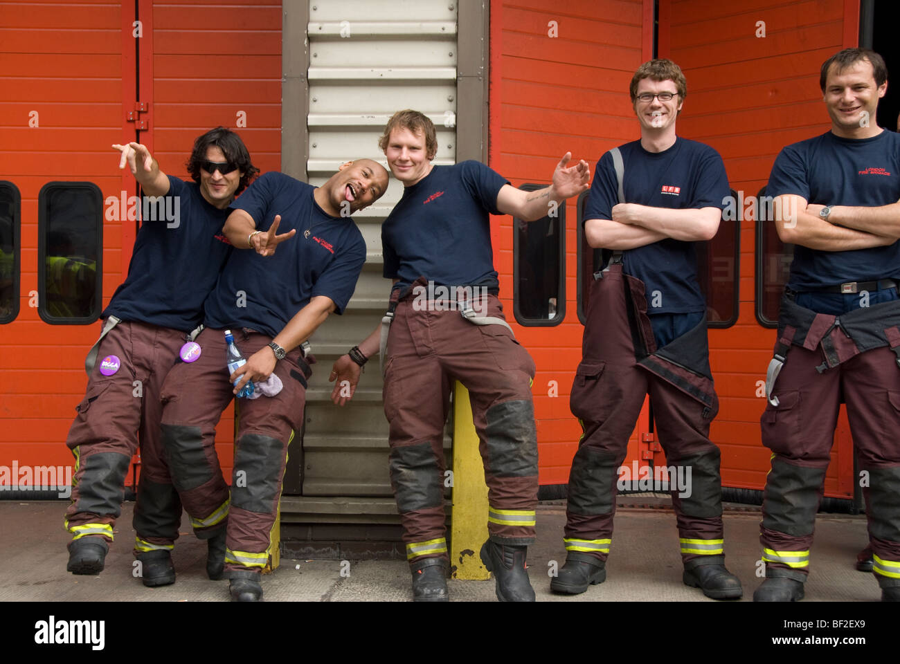 Group of firemen fooling around in front of fire station West London Stock Photo