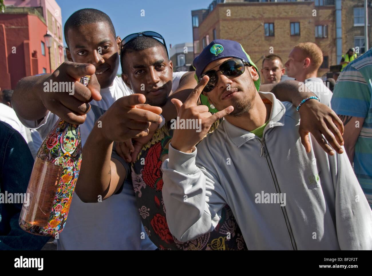 Three young men using hip hop or gangsta gestures in streets of Notting Hill Stock Photo