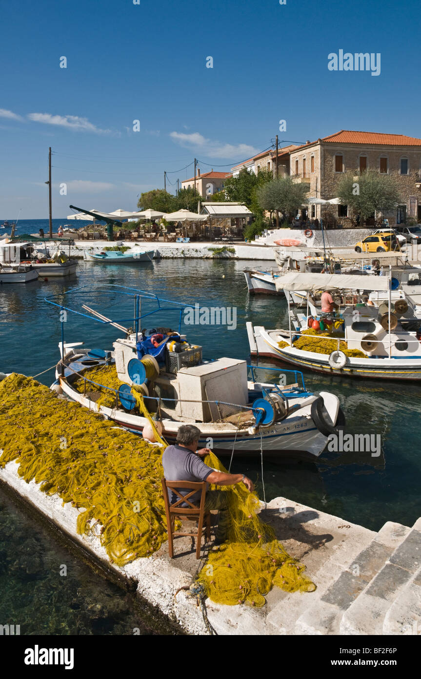 A fisherman mending nets on the quay in the little harbour at Ayios Nikolaos, in The Outer Mani, Southern Peloponnese, Greece. Stock Photo