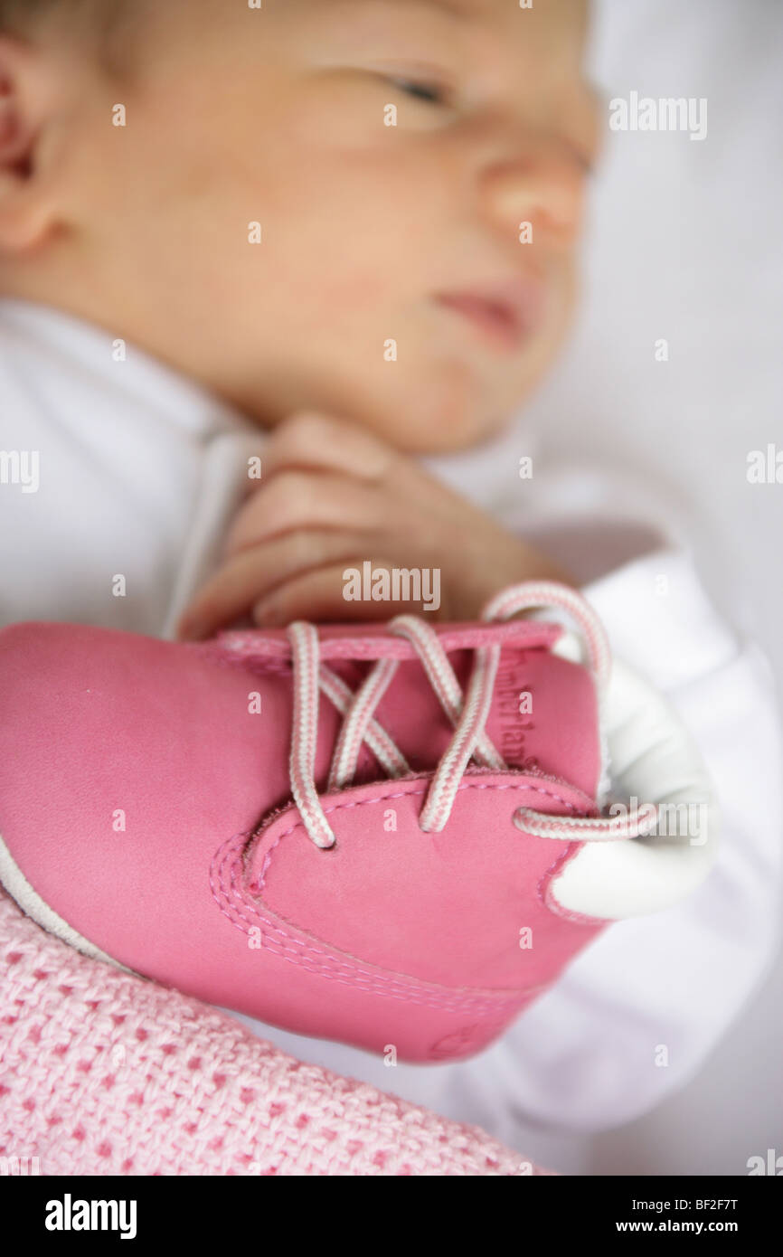 Babies first shoes with a very young baby girl out of focus in the ...