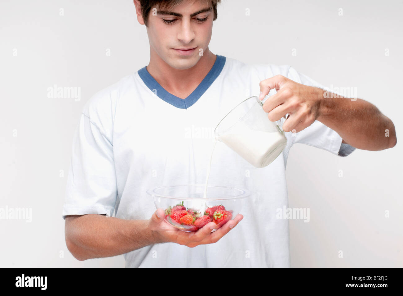 Man pouring milk on strawberries Stock Photo