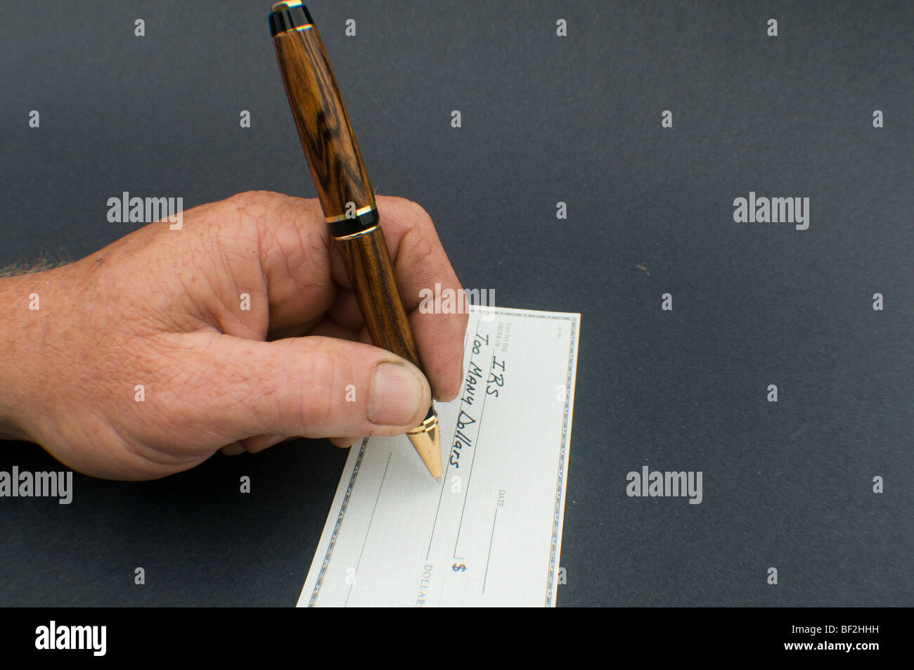 male hand writing check to IRS for Too many dollars Stock Photo Alamy