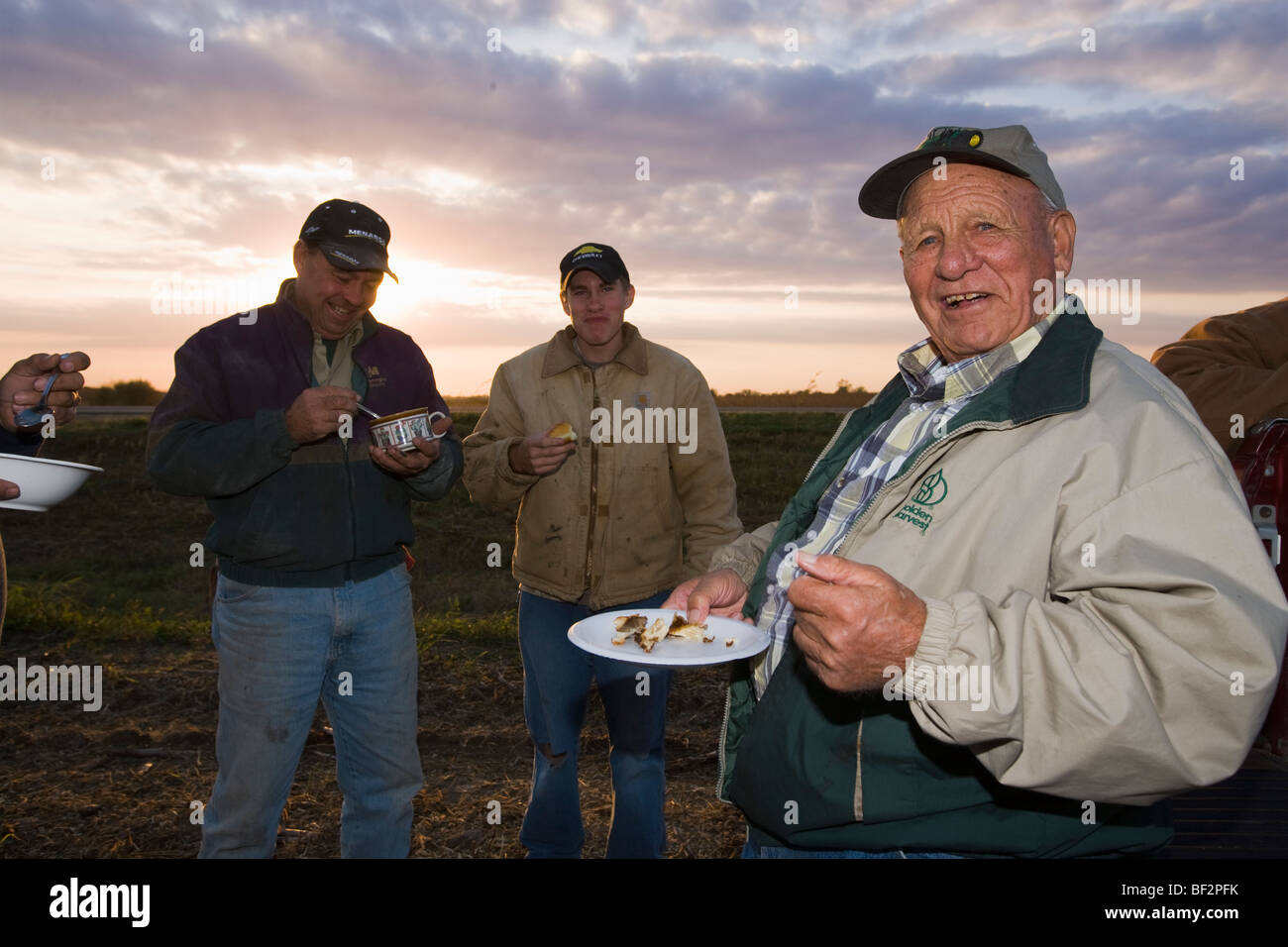 A farm family shares a meal together in the field during the long days of Autumn harvest / near Northland, Minnesota, USA. Stock Photo