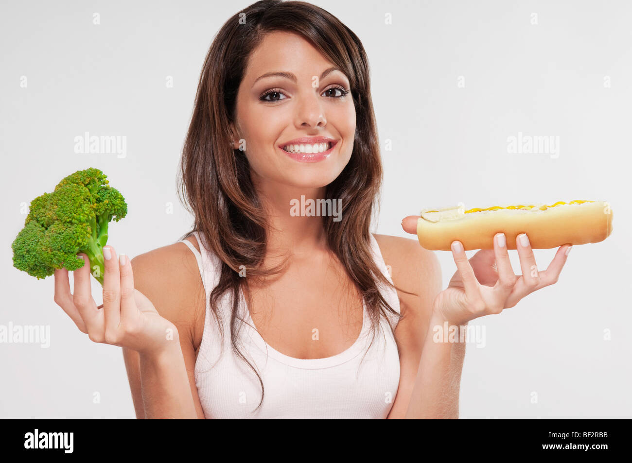 Woman choosing between broccoli and a hot dog Stock Photo Alamy