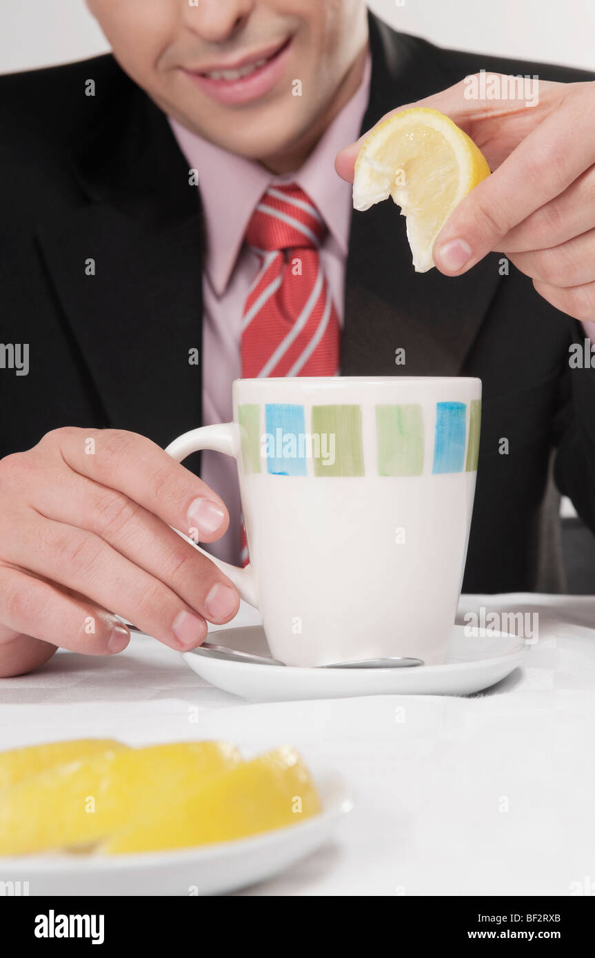Businessman squeezing lemon into tea Stock Photo - Alamy