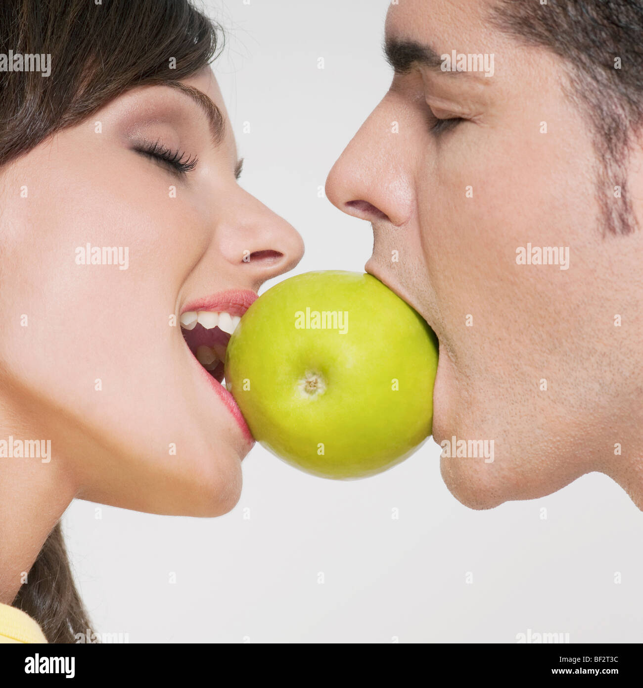 Couple biting into a green apple Stock Photo