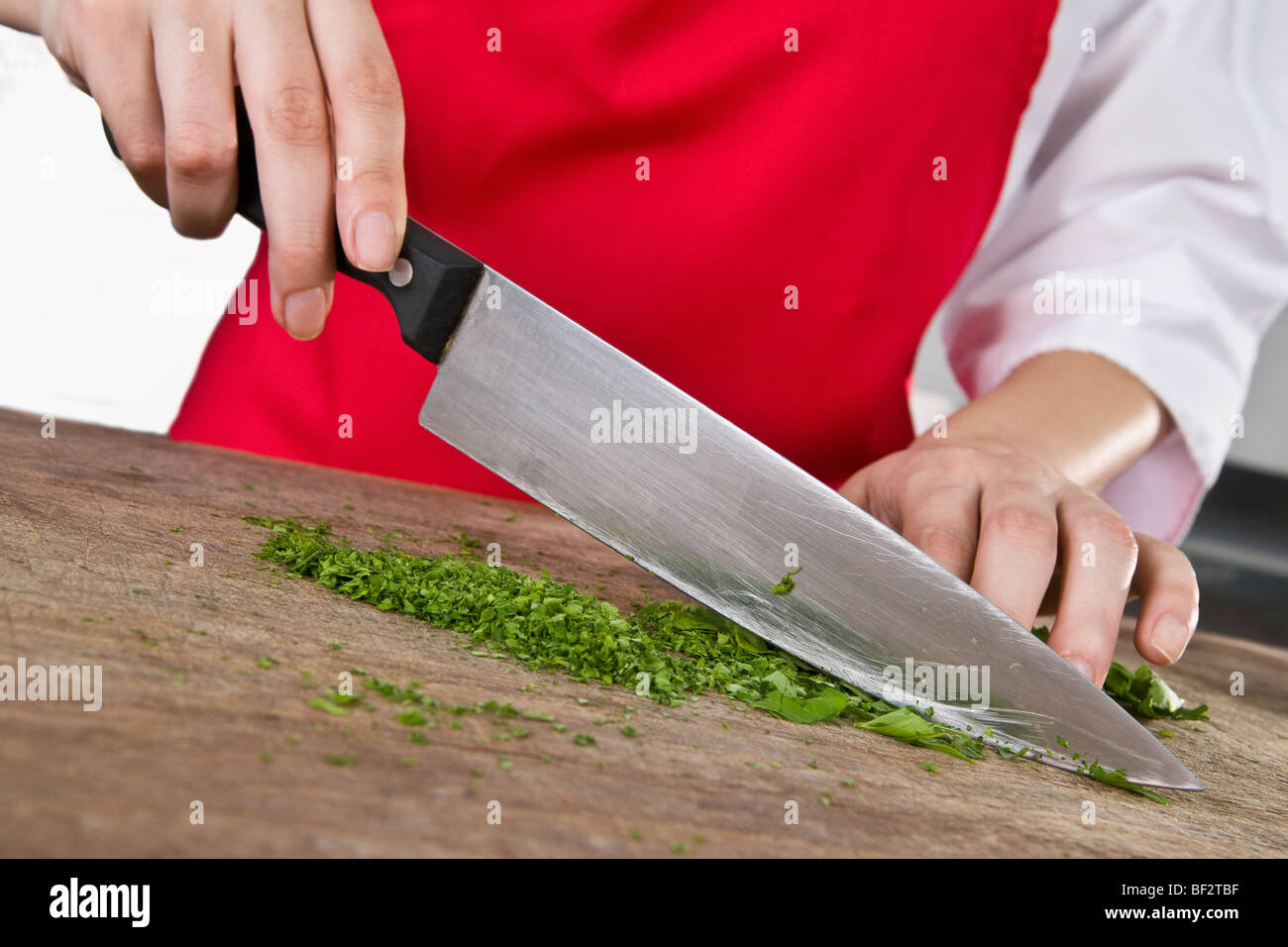 Mid section view of a female chef chopping cilantro leaves with a knife