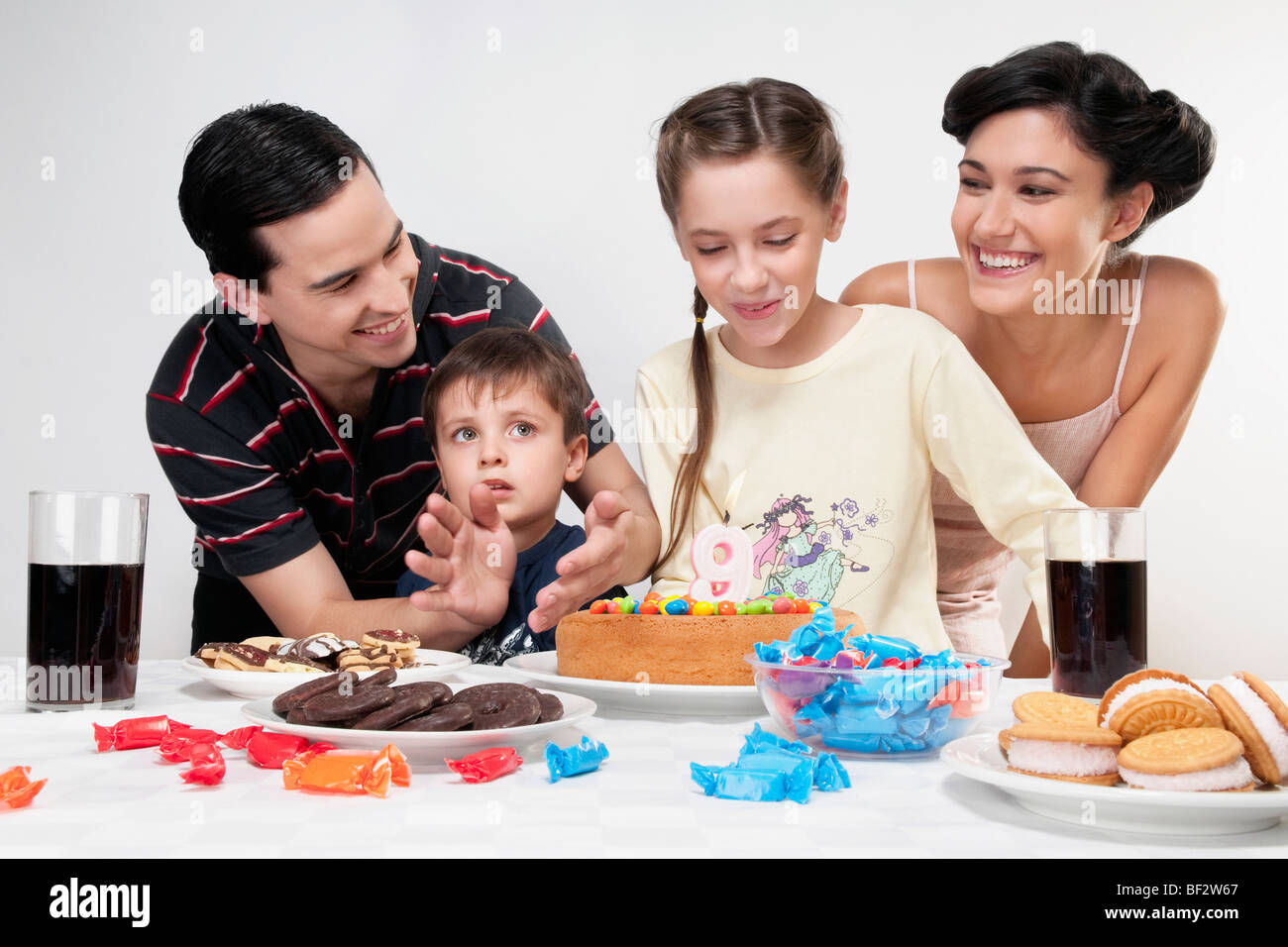 Girl blowing out birthday candles with their family Stock Photo