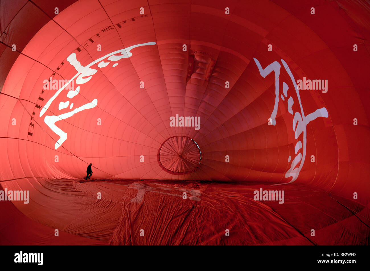 Wide angle view looking inside a hot air balloon as it is being inflated with the balloon pilot walking inside Stock Photo