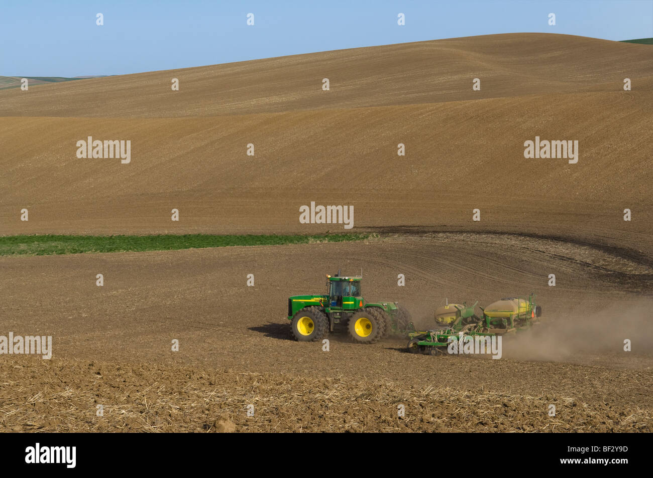 A John Deere tractor and air seeder planting garbanzo beans (chick peas) in the rolling hills of the Palouse / Washington, USA. Stock Photo