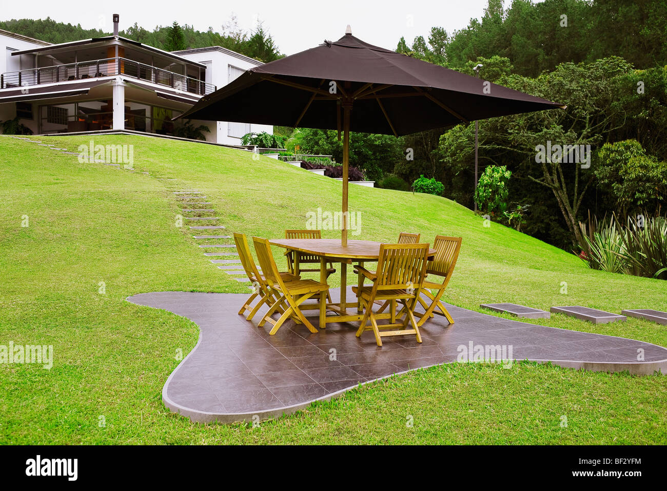 Table and chairs under a patio umbrella in a lawn Stock Photo