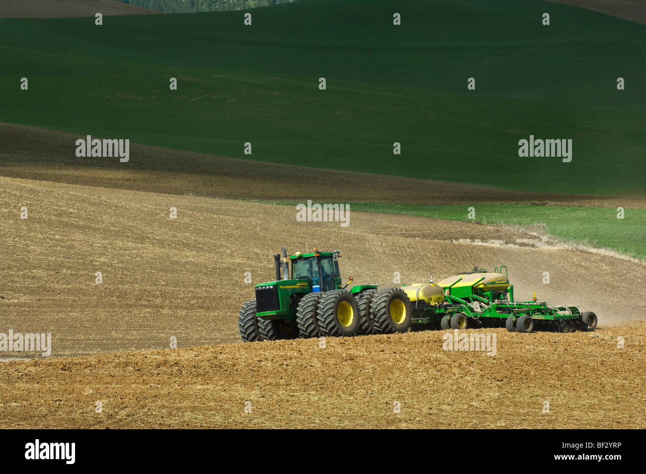 A John Deere tractor and air seeder planting garbanzo beans (chick peas ...