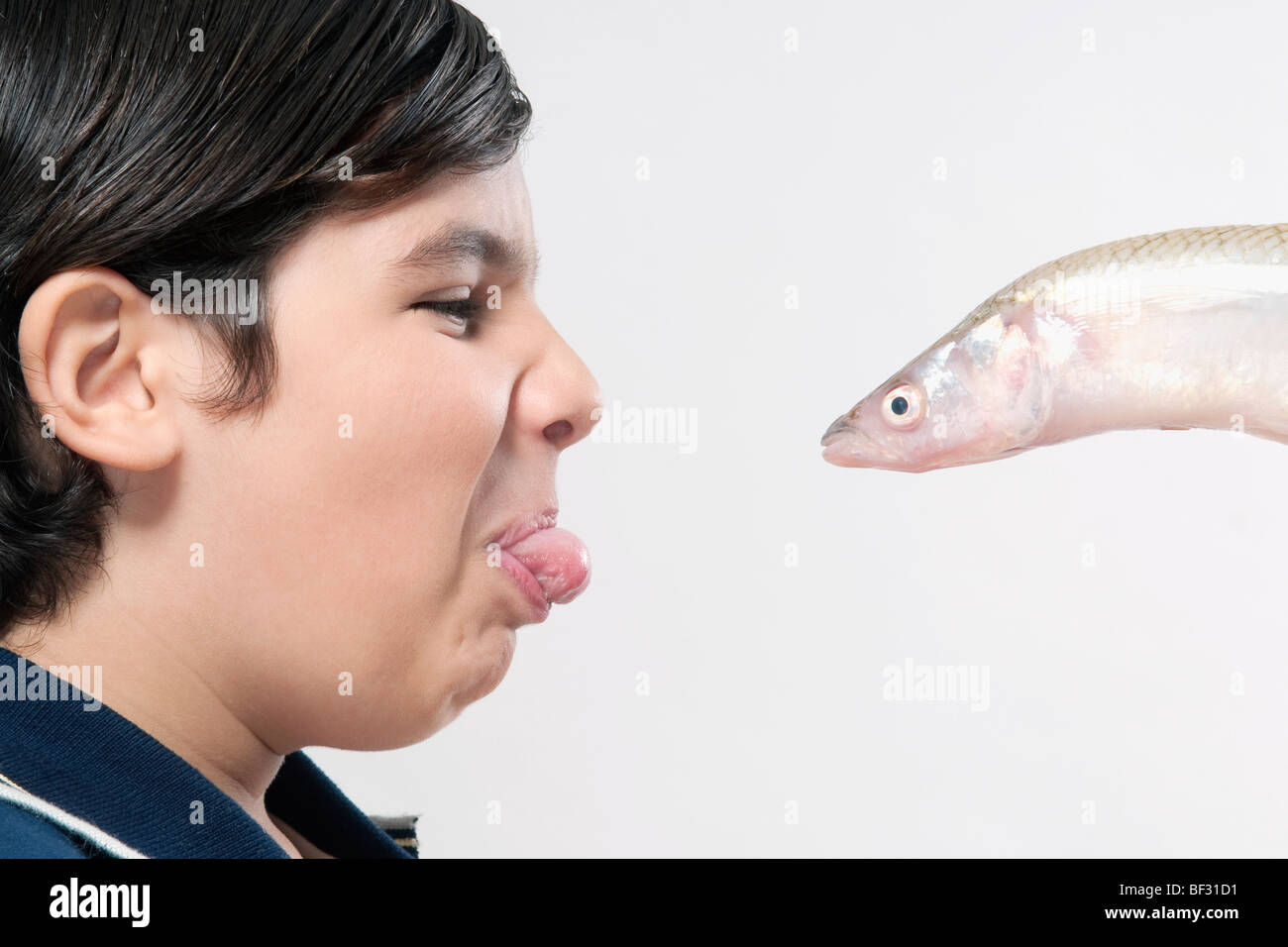 Boy facing a fish and making a disgust face Stock Photo