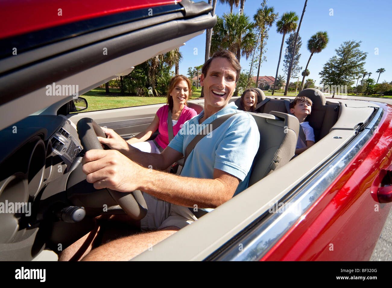 A family of four, mother, father, son and daughter driving in a ...