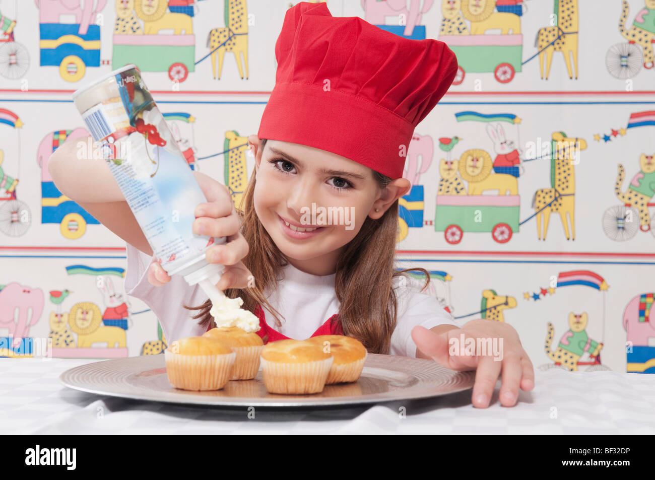 Portrait of a girl putting whipped cream on cupcakes Stock Photo - Alamy