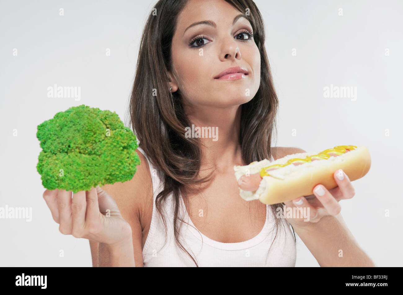 Woman choosing between broccoli and a hot dog Stock Photo Alamy