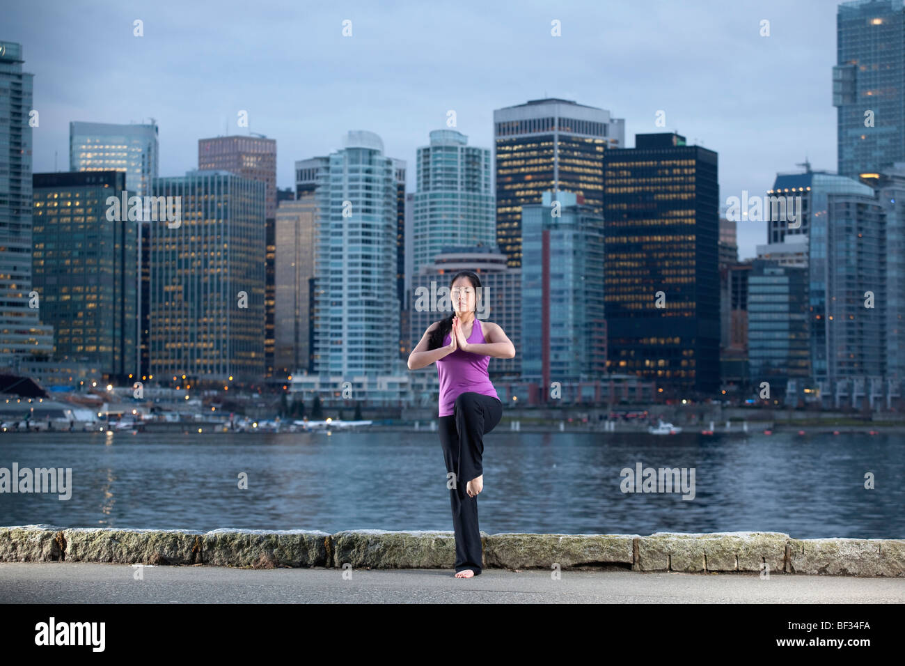 A young woman does yoga, the Vrksasana Tree Pose, with Vancouver