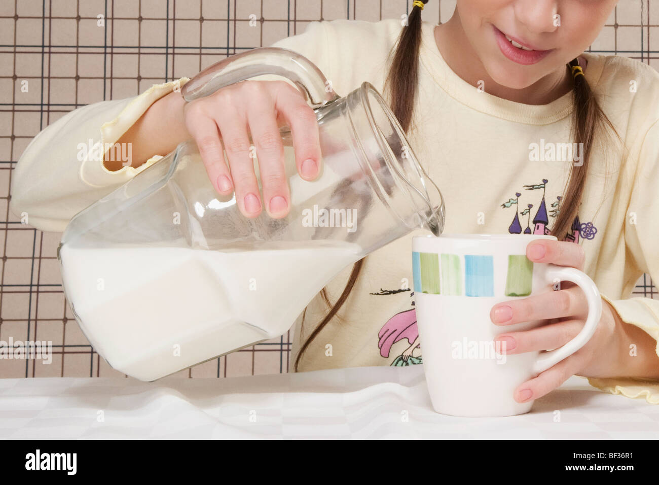 Girl pouring milk into a cup Stock Photo