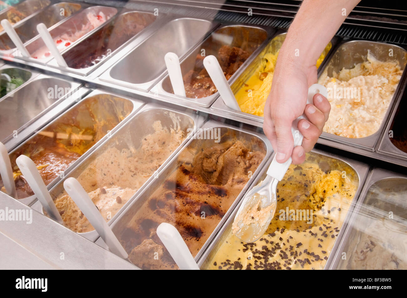 Man's hand taking scoop of ice cream out of container Stock Photo