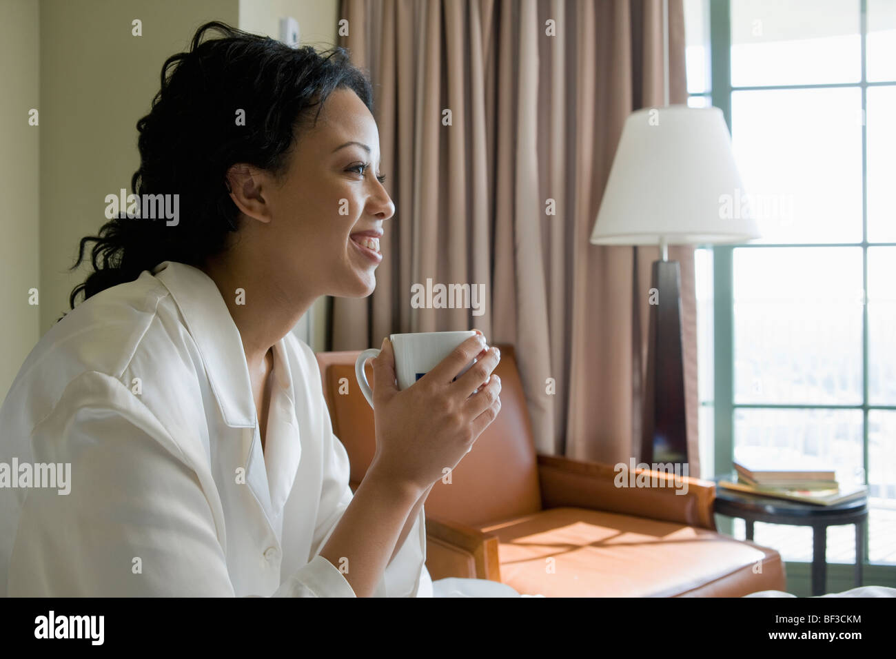 African woman drinking coffee in bedroom Stock Photo - Alamy