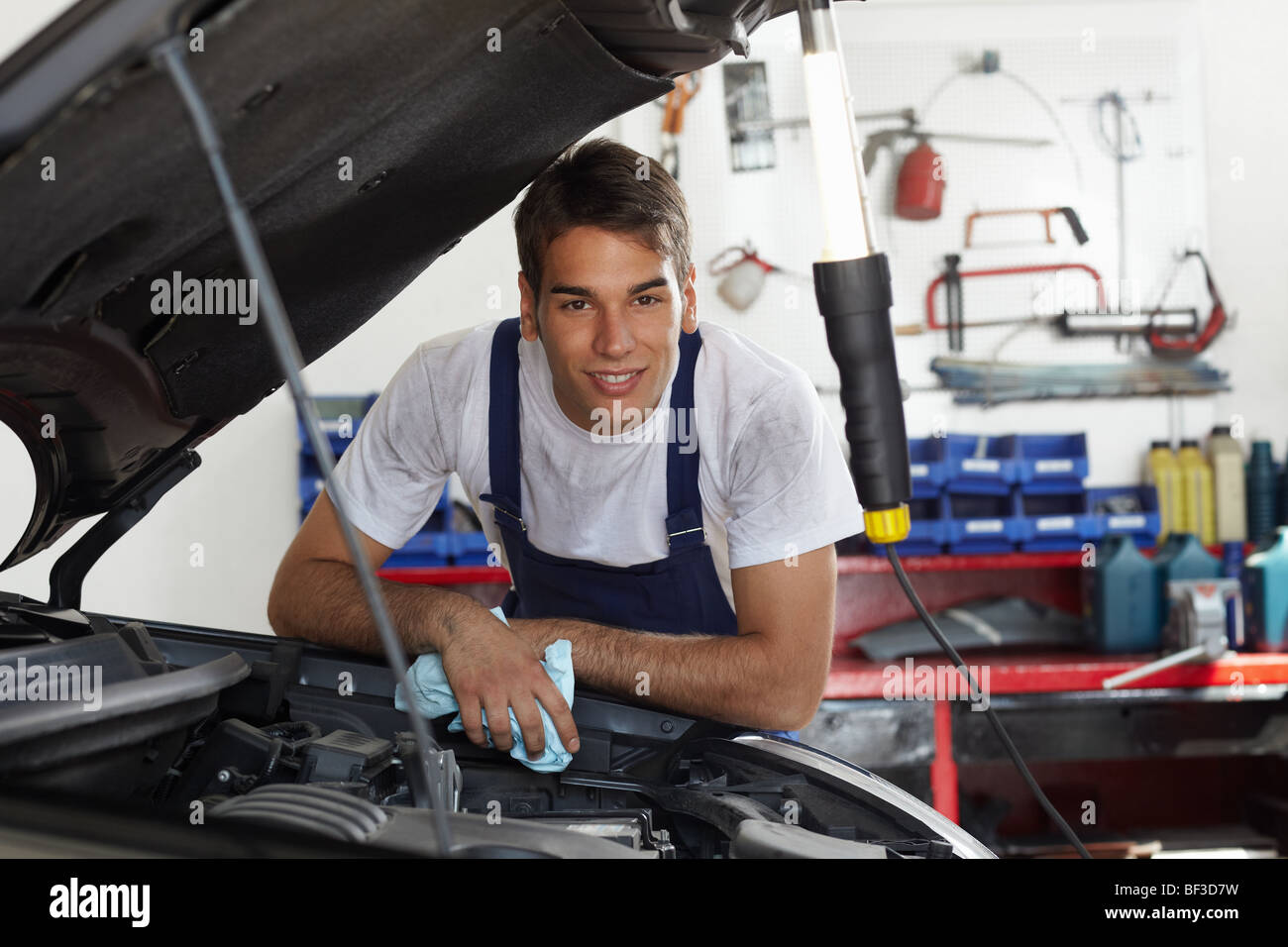 mechanic leaning on bonnet Stock Photo