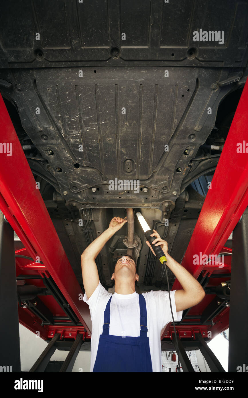 mechanic standing under car engine and holding lamp. Copy space Stock Photo