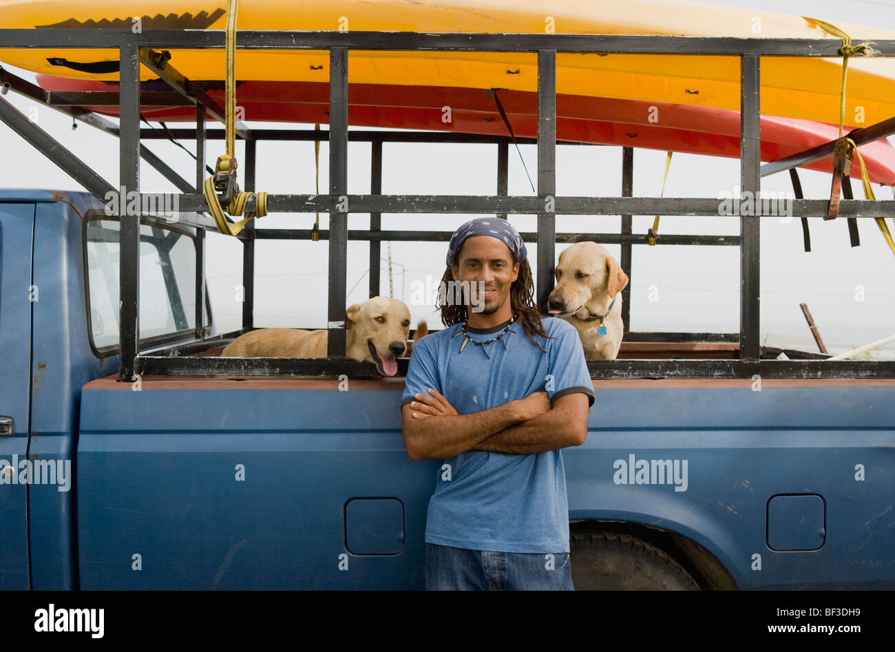 Hispanic man with dogs leaning against truck Stock Photo