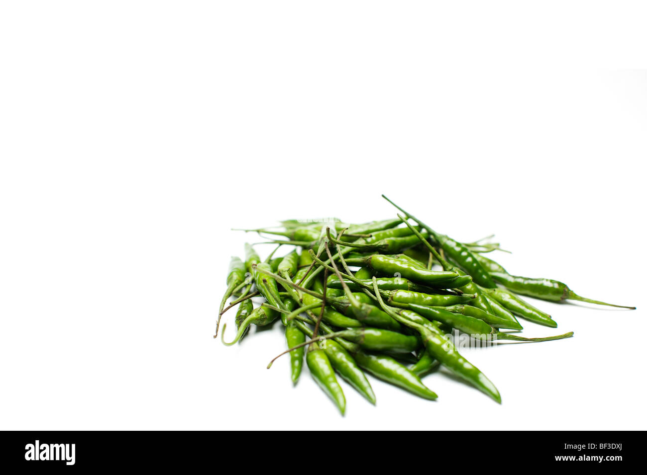 Pile of green birds eye chillies against a white background Stock Photo