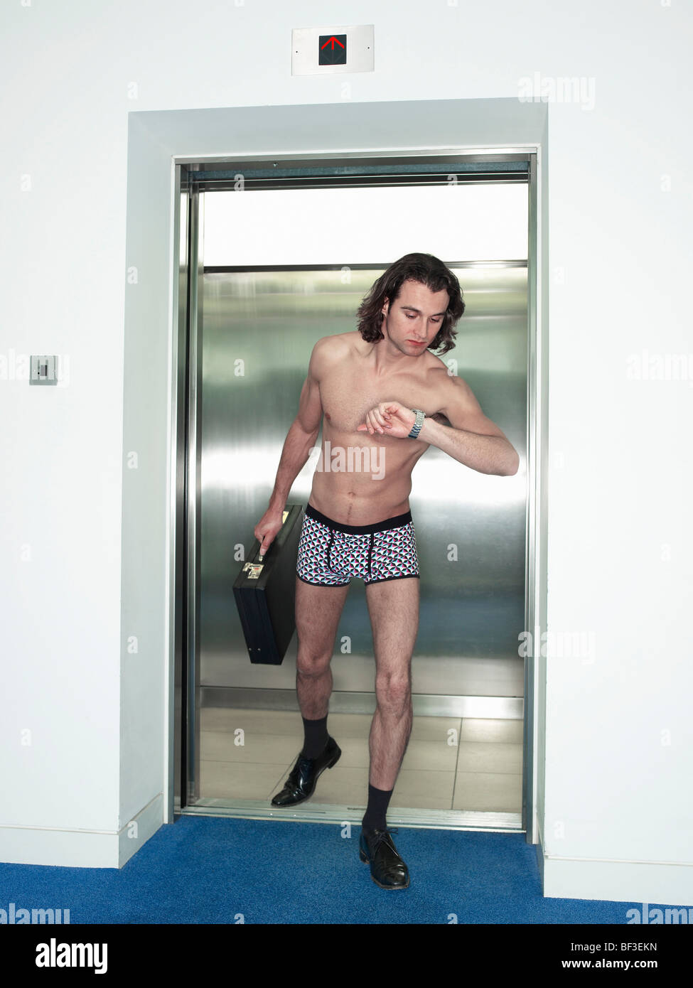man in underwear walking out of a lift Stock Photo