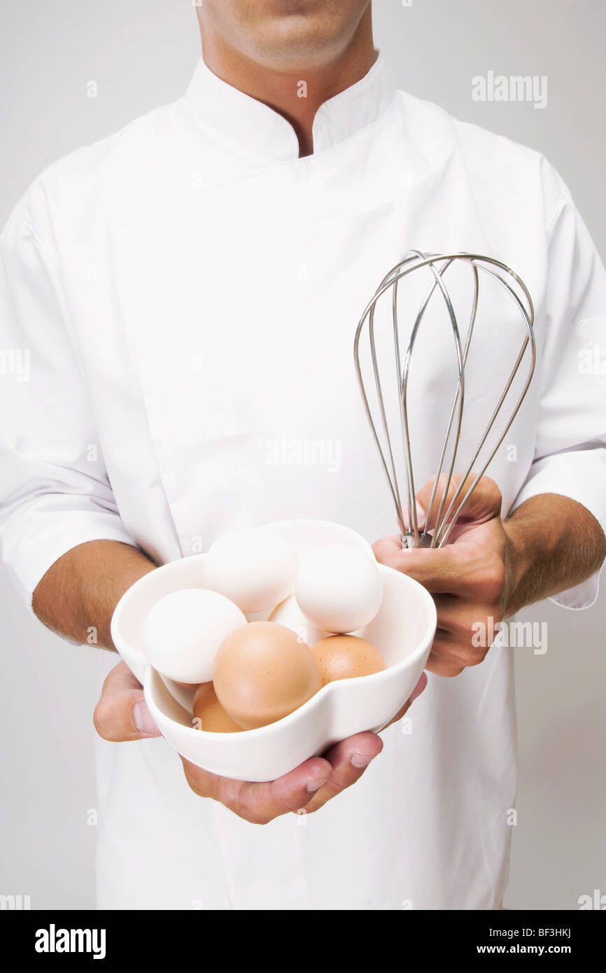 Man holding a bowl of eggs and a wire whisk Stock Photo
