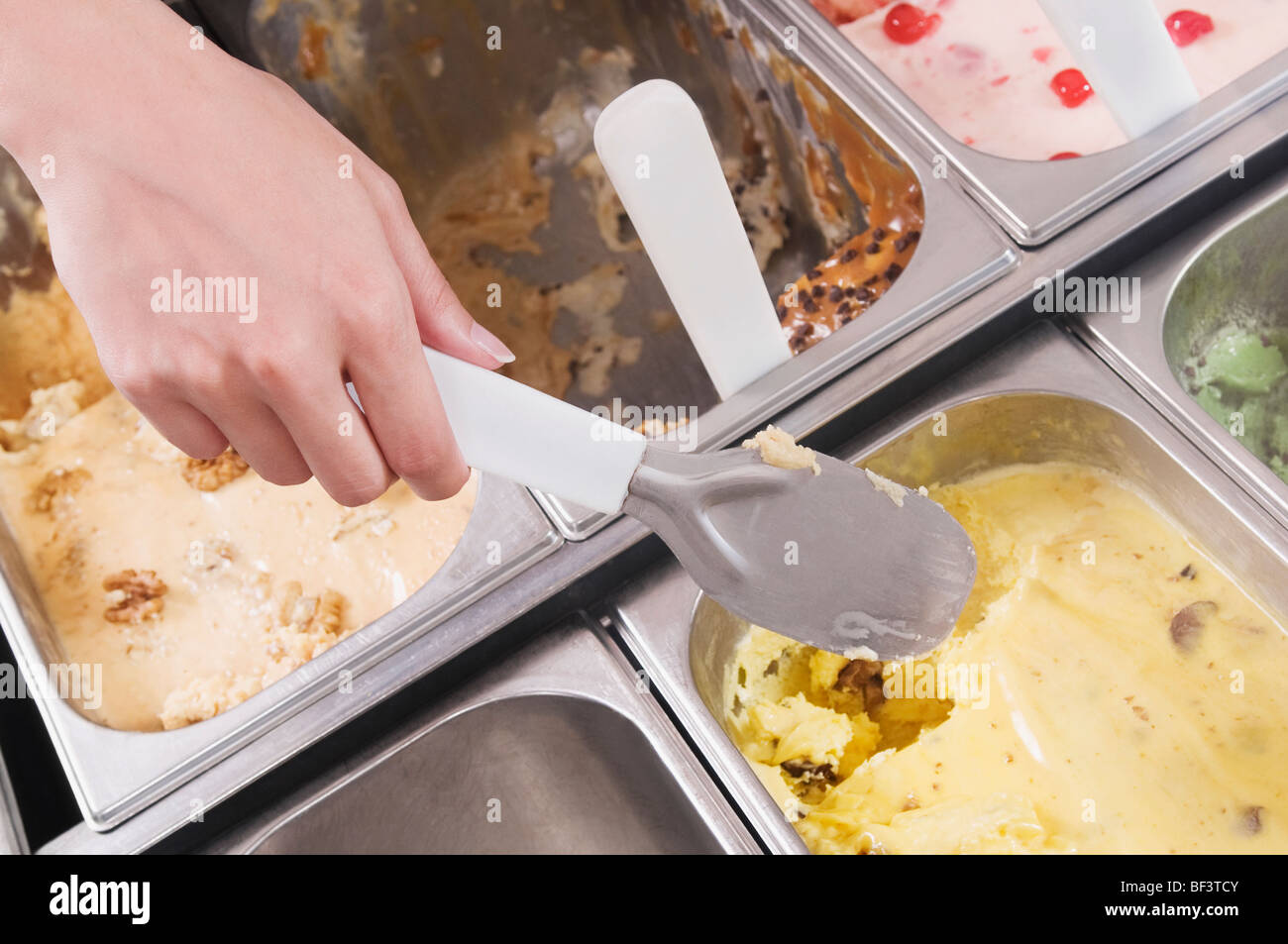 Man's hand taking scoop of ice cream out of container Stock Photo