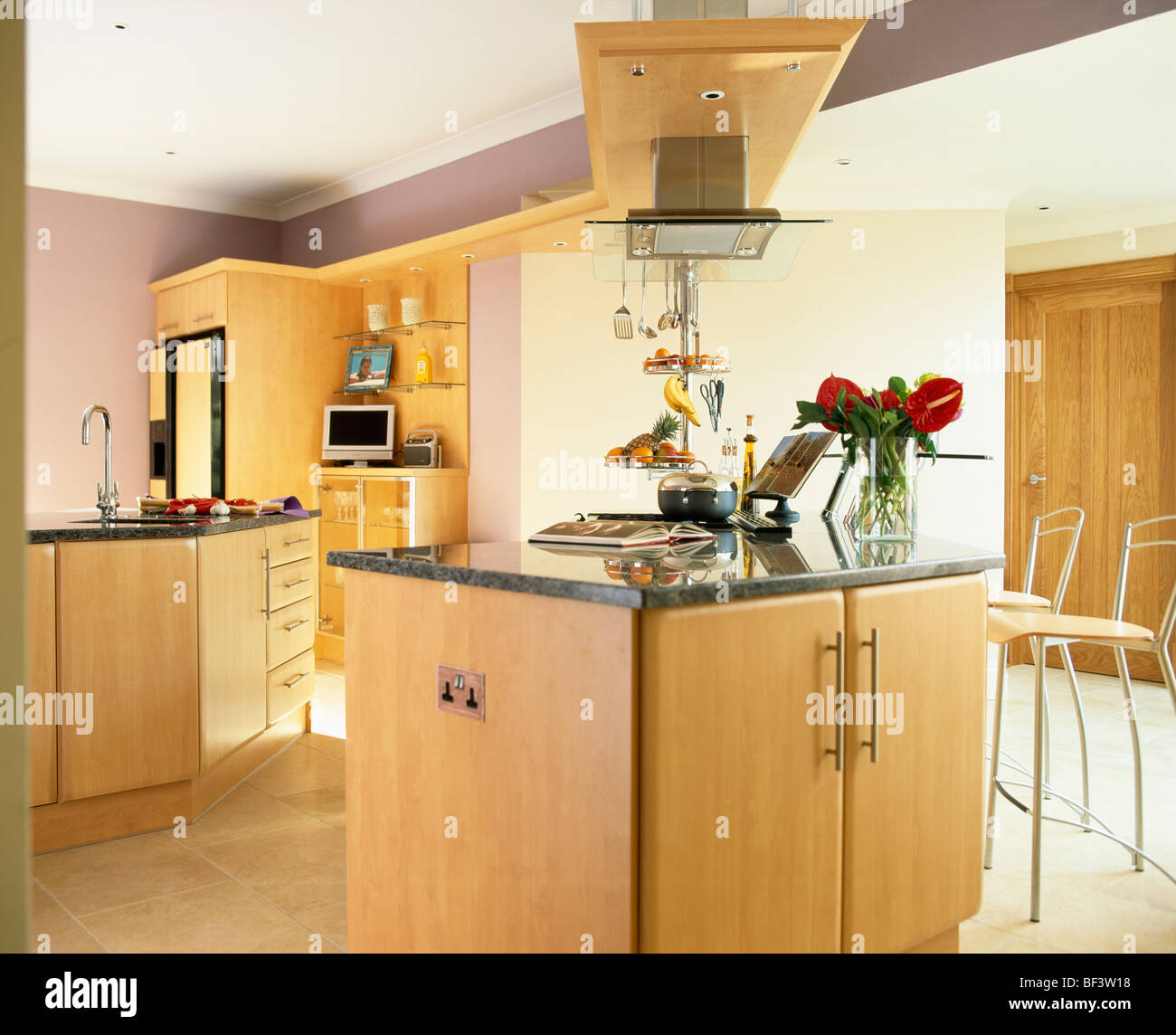 Granite worktop on pale wood island unit in modern mauve country