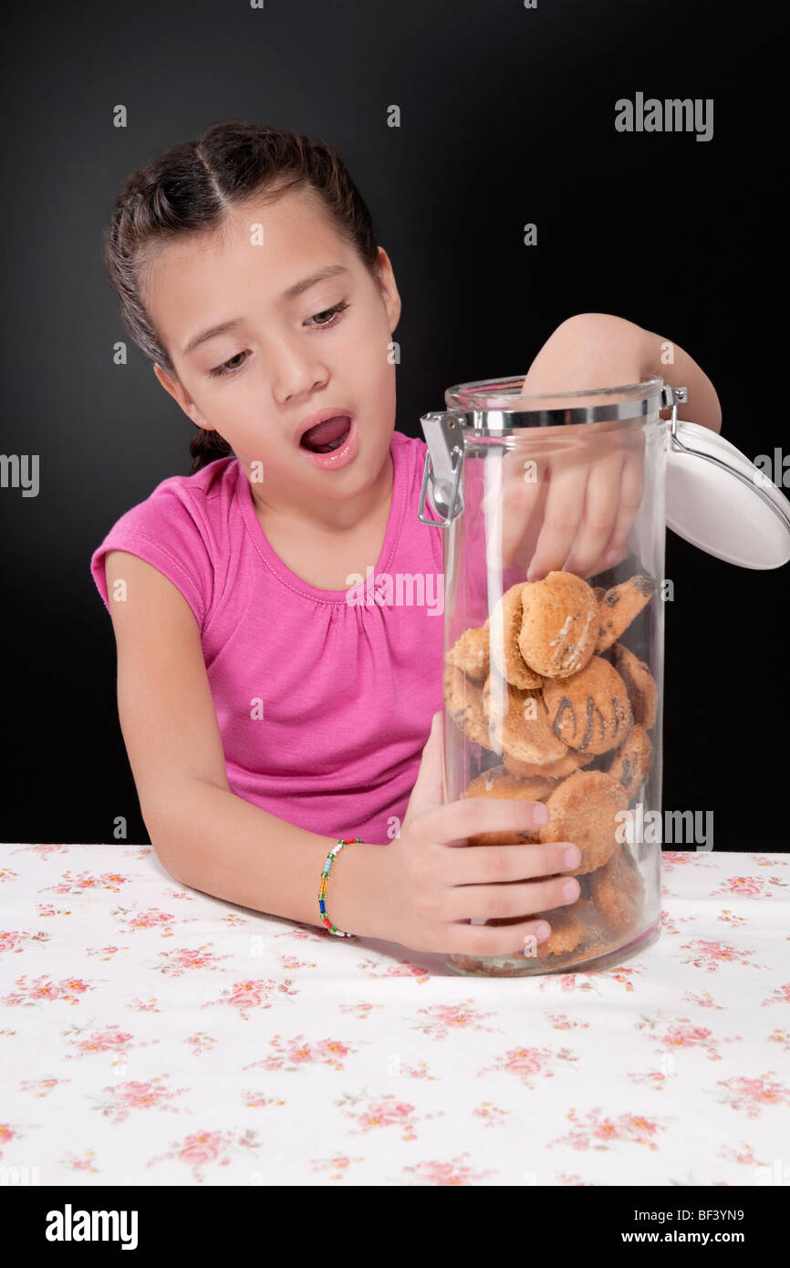 Girl putting her hand into a cookie jar Stock Photo