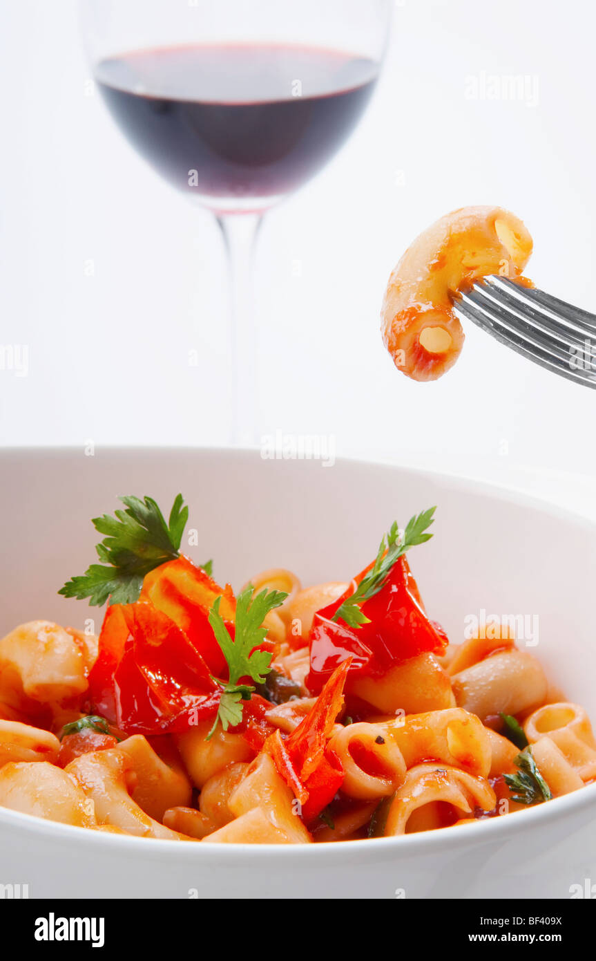 Closeup of macaroni in tomato sauce with a glass of red wine Stock