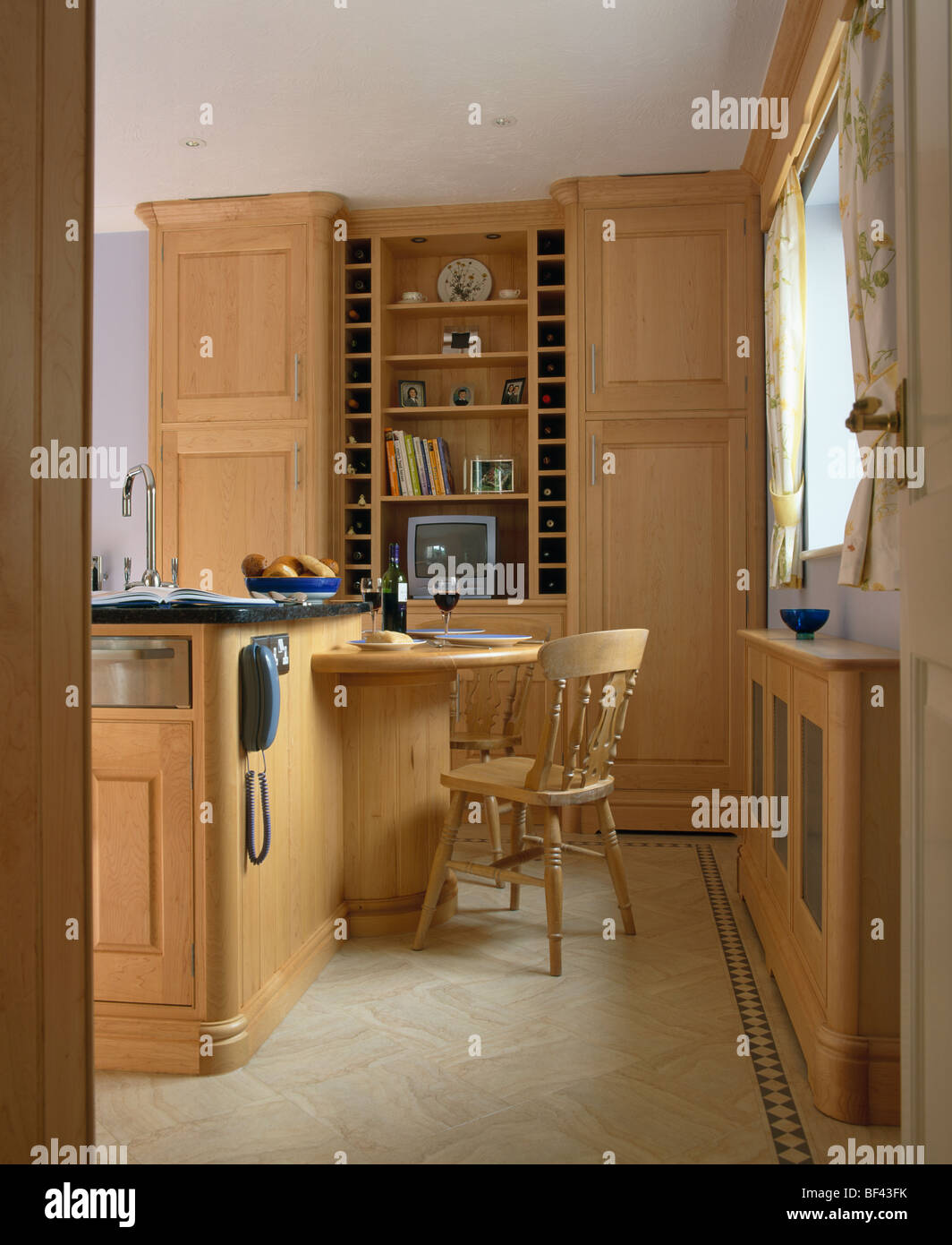 Pale wood fitted wood units in modern kitchen with wooden chair at ...