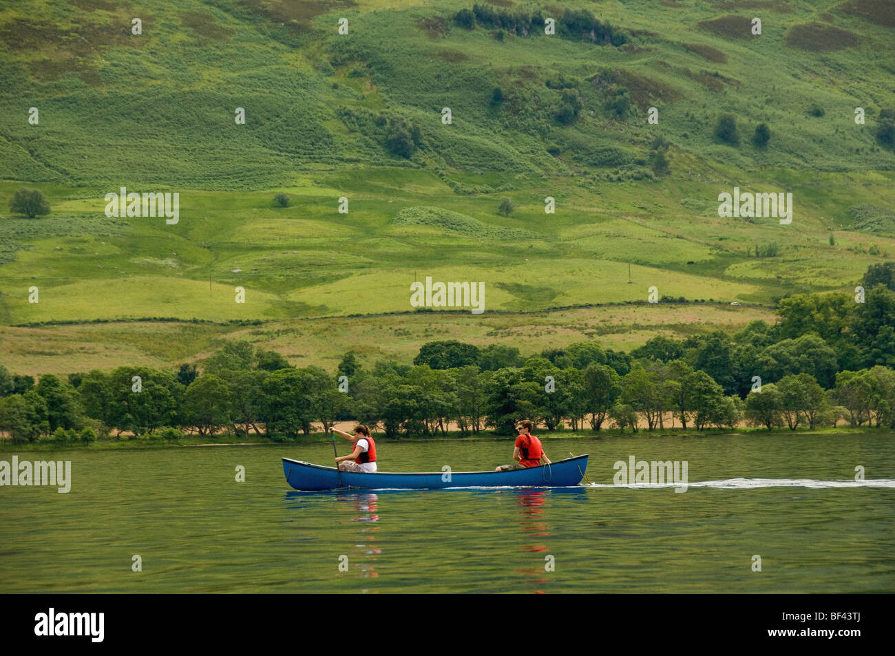 Side view of 2 young caucasian adults paddling a Canadian canoe on a