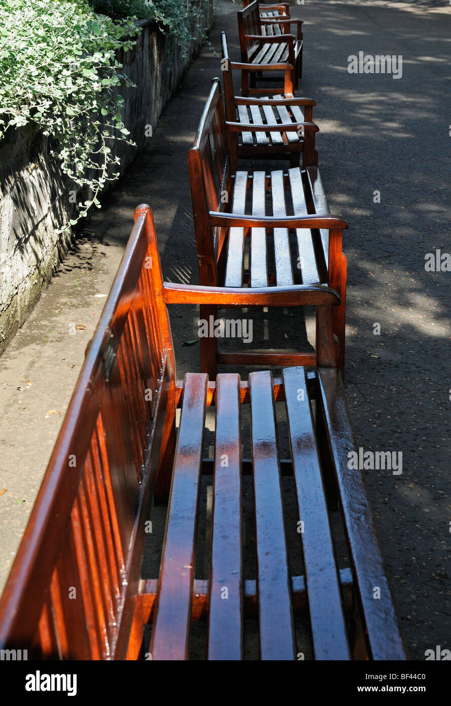 line of empty brown colored coloured wooden park benches princes street gardens edinburgh scotland Stock Photo