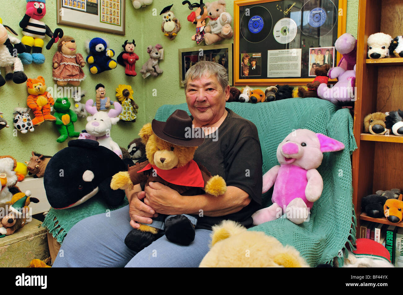 Elderly woman sitting with her soft toy collection in her living room Stock Photo