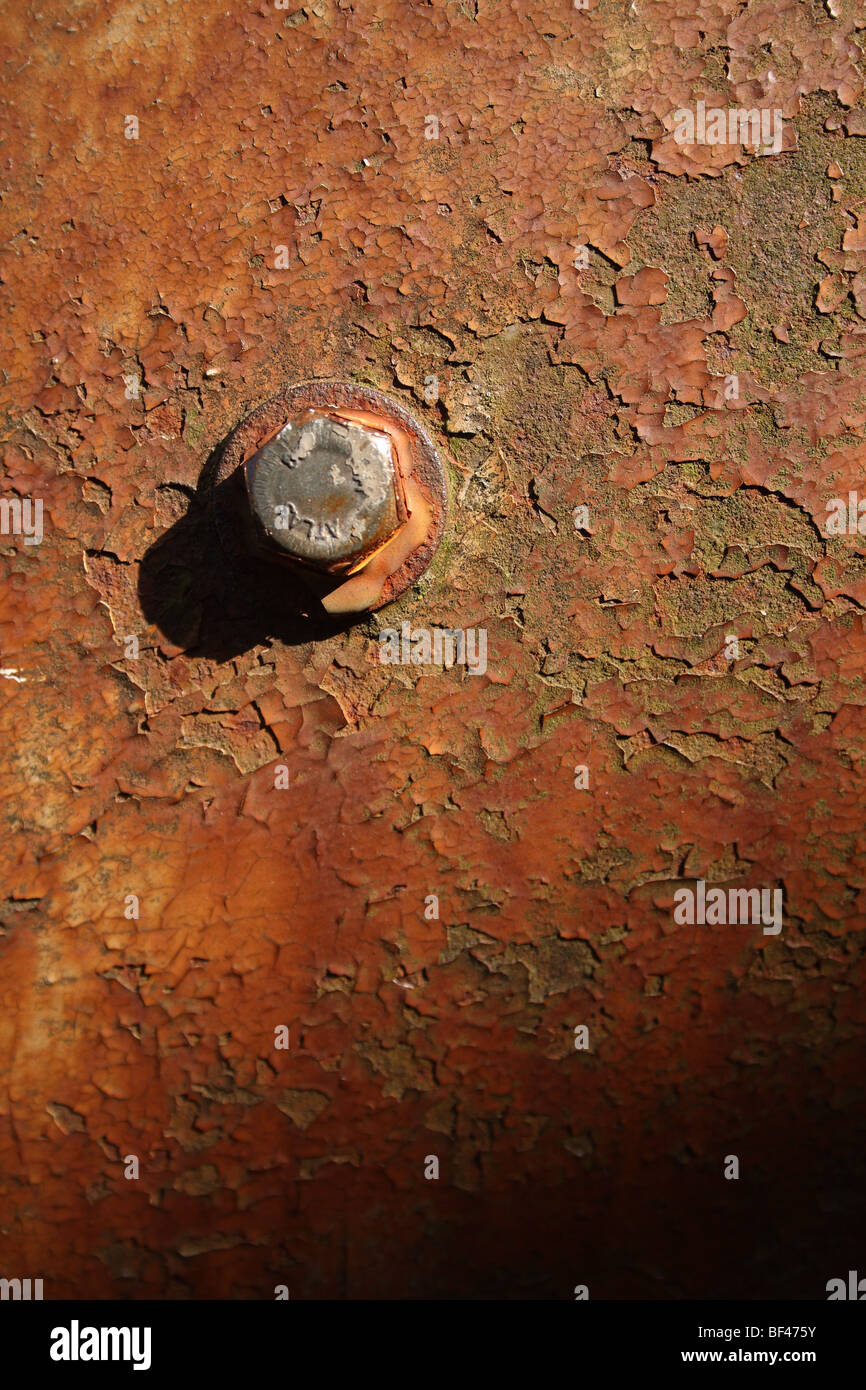 Close-up of hexagonal bolt head on rusty flaking steel mud-guard / fender on old Massey Ferguson tractor at Scorton, Lancashire, United Kingdom. Stock Photo