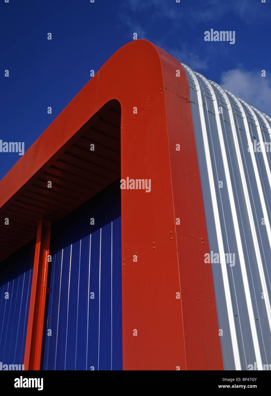 Red and blue colour scheme on corner detail of modern industrial warehouse factory building Stock Photo