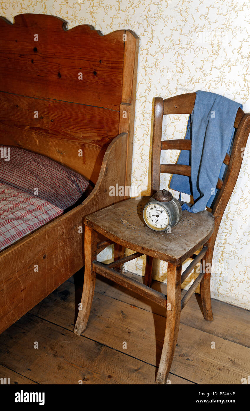 Old alarm clock on a wooden chair next to a farmer's wooden bed, bed-chamber in the Hof Reisch farm from 1780, Wolfegg farmhous Stock Photo
