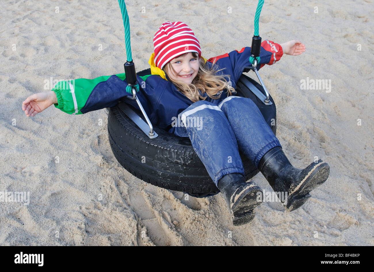Little girl, 7 years, sitting in a tire swing Stock Photo