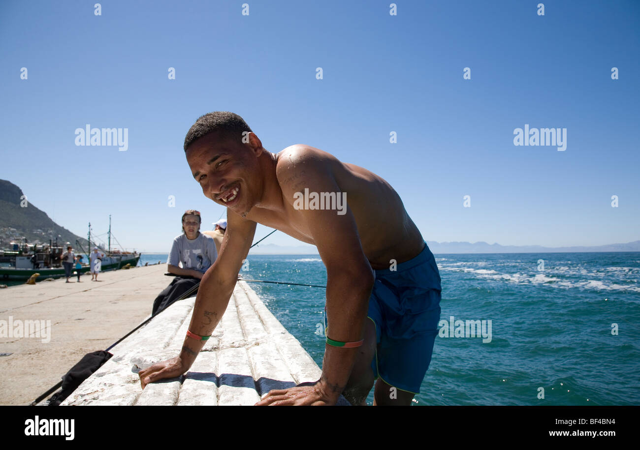 Man climbing out of water at Kalk bay - Cape Town Stock Photo