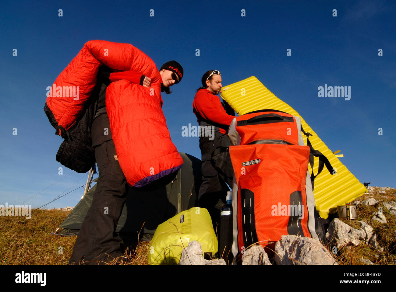 Hikers, young man and woman buildig a bivouac with tent, sleeping bag, backpack and sleeping pad, Mt. Heidachstellwand, Rofan,  Stock Photo