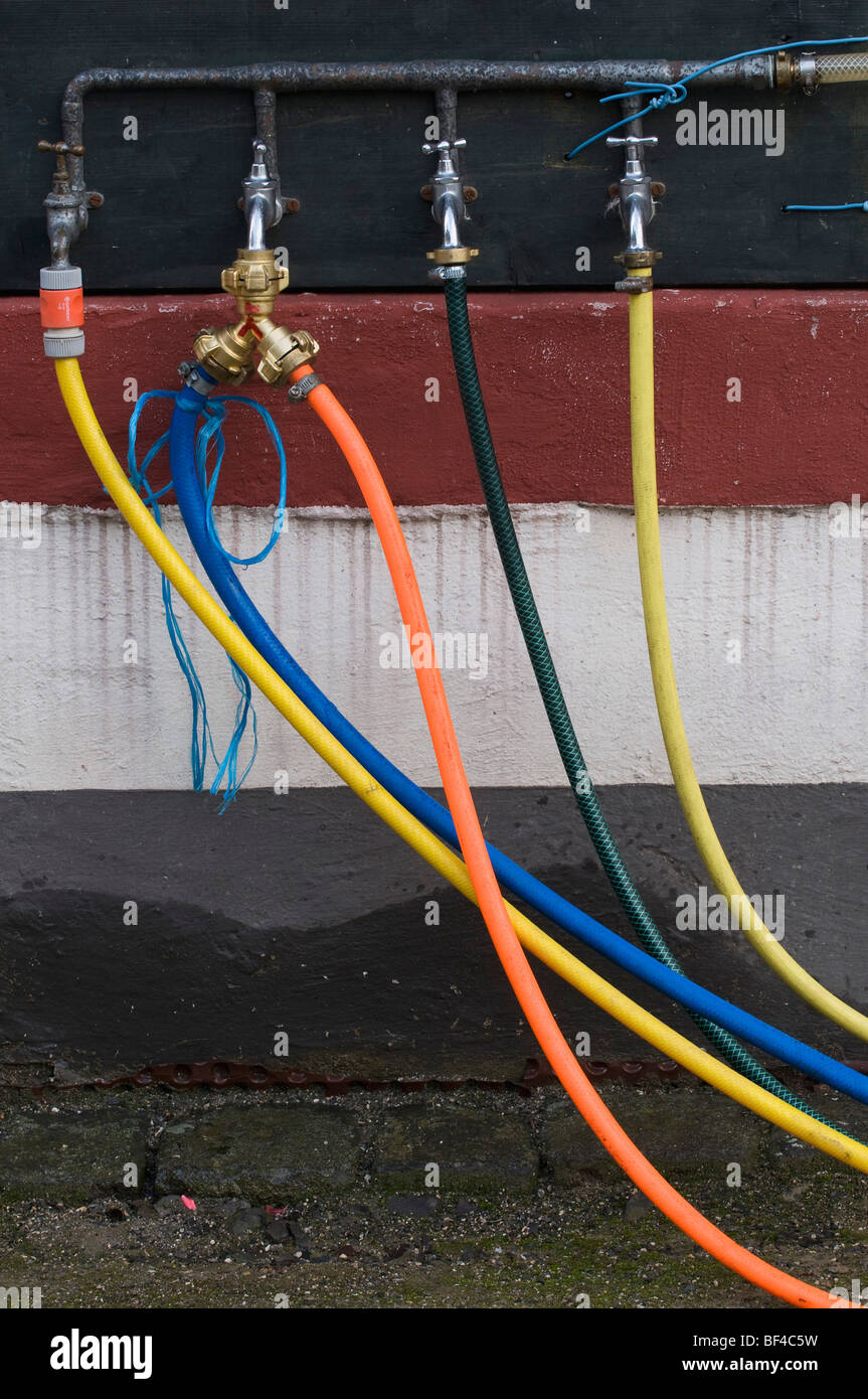 Water scarcity, four leaky faucets, one with a double junction and five coloured hoses Stock Photo