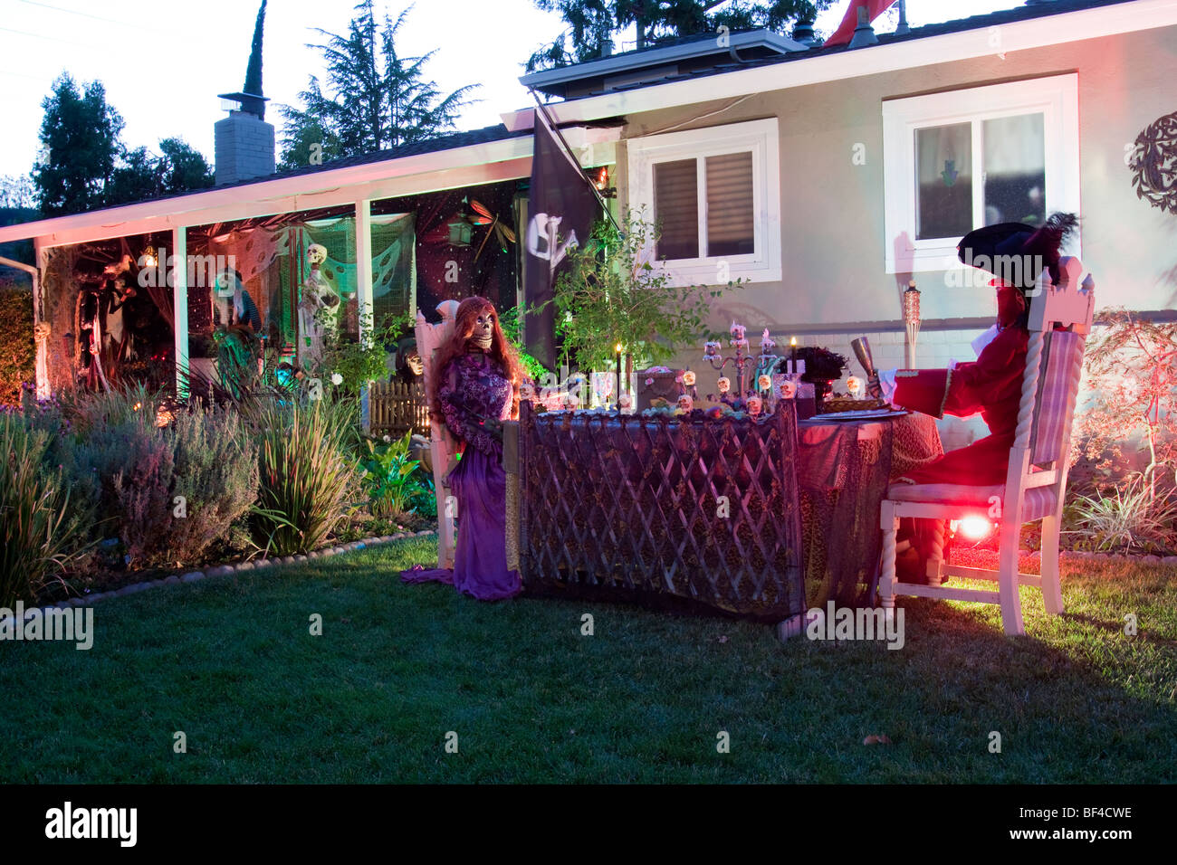 Skeletons dressed up sitting at dinner table as part of elaborate Halloween display on a house front lawn Stock Photo